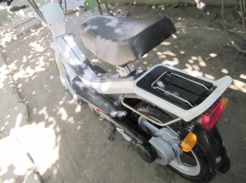 Minor prins conducând un moped pe uliţele satului